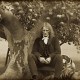 An old photograph of a man sitting under an apple tree.